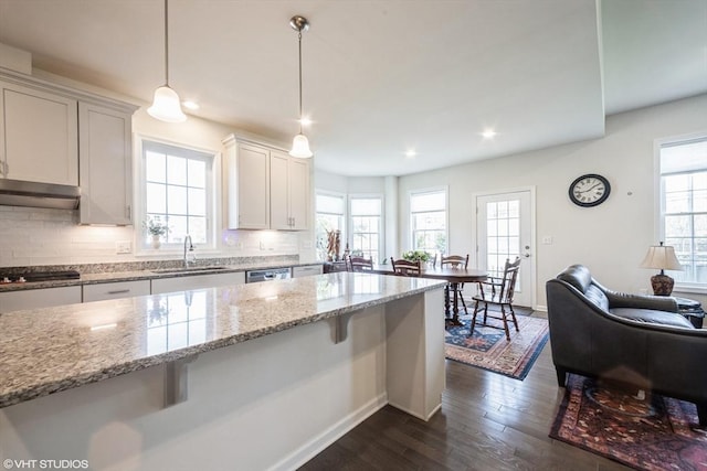 kitchen featuring appliances with stainless steel finishes, a sink, baseboards, decorative backsplash, and dark wood-type flooring