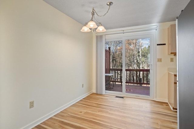 unfurnished dining area with light wood-type flooring and an inviting chandelier