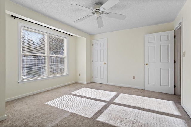 unfurnished bedroom with ceiling fan, light colored carpet, and a textured ceiling