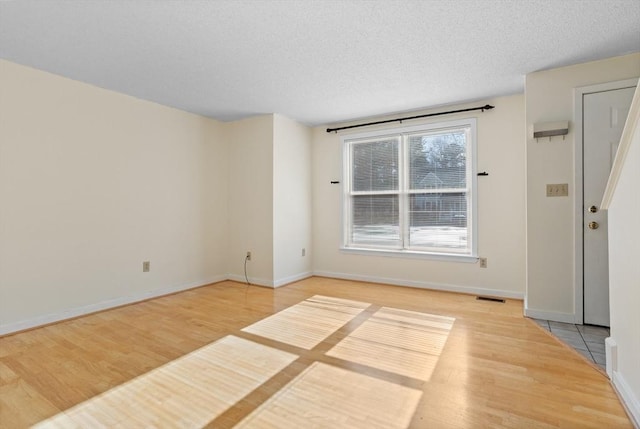 spare room with a textured ceiling and hardwood / wood-style flooring