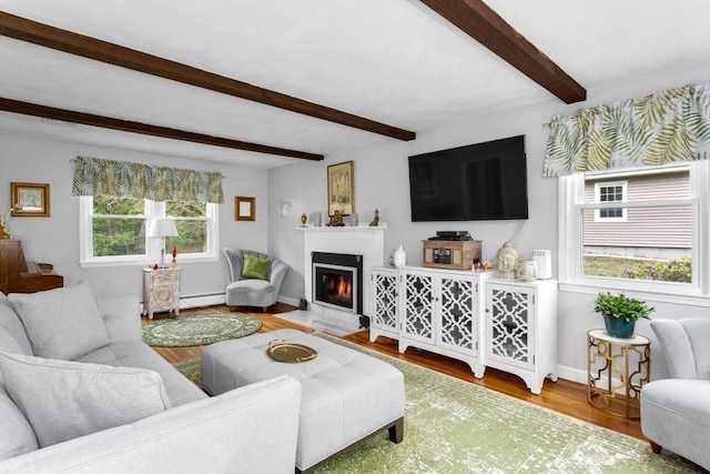 living room with wood finished floors, beam ceiling, baseboards, a baseboard heating unit, and a glass covered fireplace