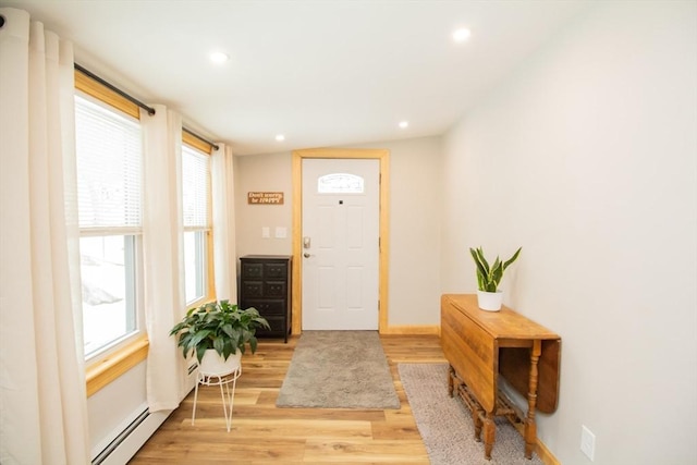 doorway to outside featuring light wood-type flooring, a baseboard radiator, a wealth of natural light, and recessed lighting