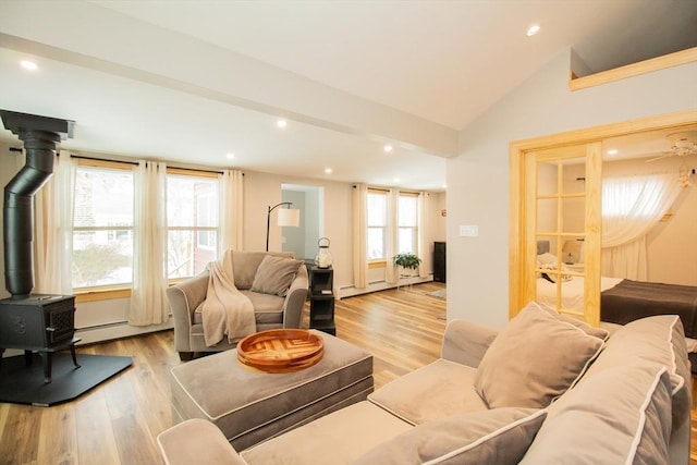 living room with light wood-style floors, lofted ceiling, a wood stove, and a healthy amount of sunlight