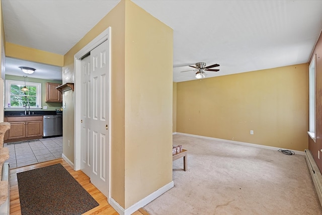 hall with sink, baseboard heating, and light tile patterned floors