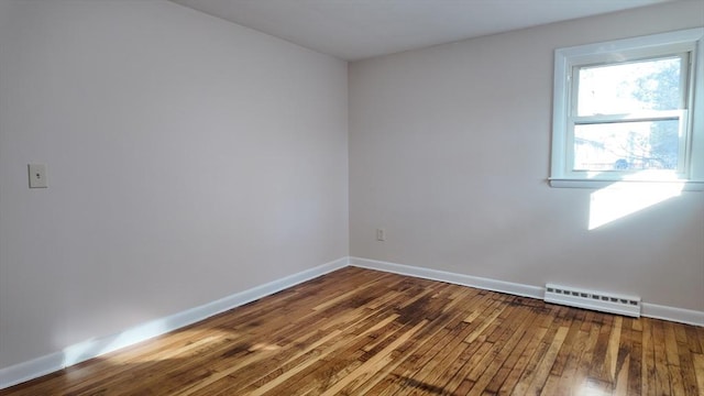 unfurnished room with baseboard heating and hardwood / wood-style floors