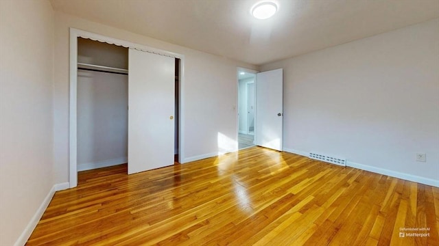 unfurnished bedroom with hardwood / wood-style floors and a closet