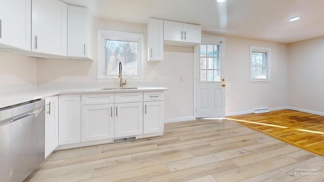 kitchen featuring dishwasher, light hardwood / wood-style floors, white cabinetry, and a wealth of natural light