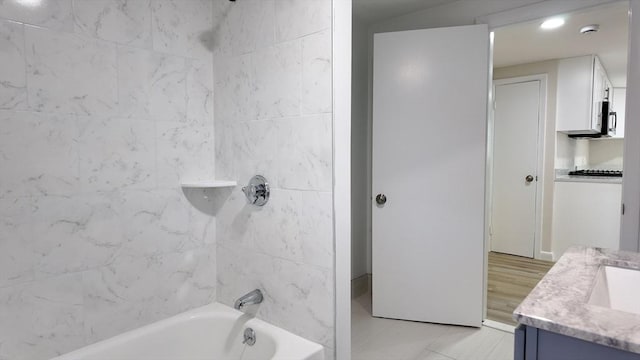 bathroom featuring tile patterned flooring, vanity, and tiled shower / bath