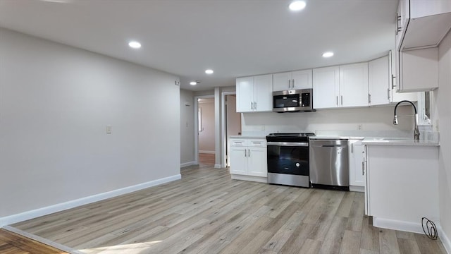 kitchen featuring white cabinets, sink, appliances with stainless steel finishes, and light hardwood / wood-style flooring