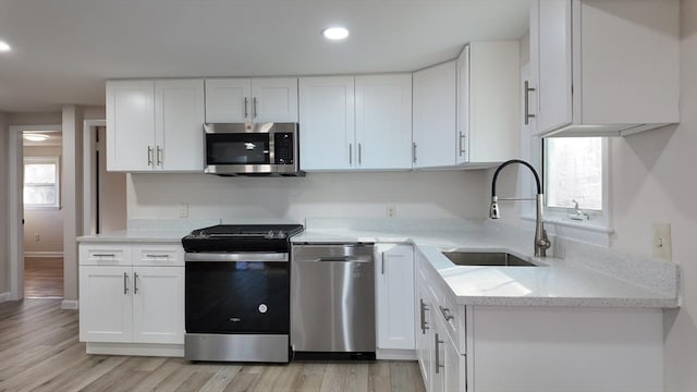 kitchen with white cabinets, sink, light wood-type flooring, and stainless steel appliances