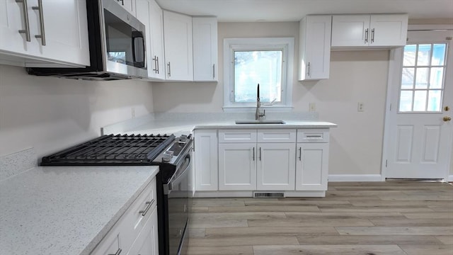 kitchen featuring white cabinetry, plenty of natural light, stainless steel appliances, and sink