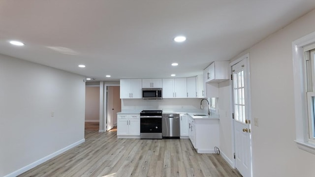 kitchen with white cabinets, sink, stainless steel appliances, and light hardwood / wood-style flooring