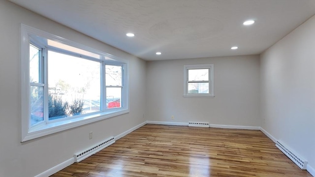 empty room with a baseboard radiator, light hardwood / wood-style flooring, and a healthy amount of sunlight