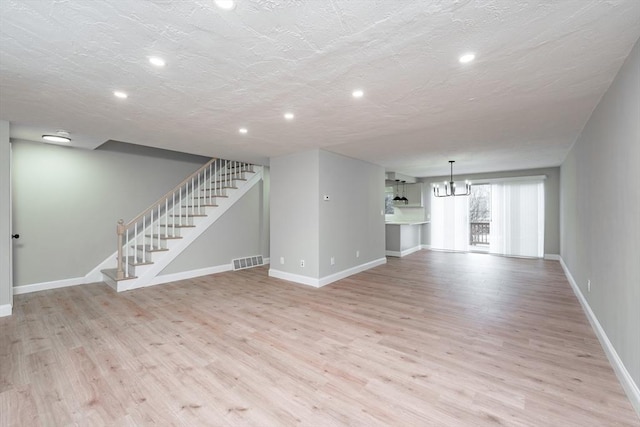 unfurnished living room with light wood-type flooring and a textured ceiling