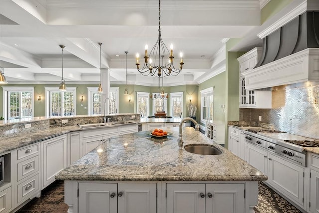 kitchen with a notable chandelier, stainless steel gas cooktop, a sink, white cabinets, and a large island