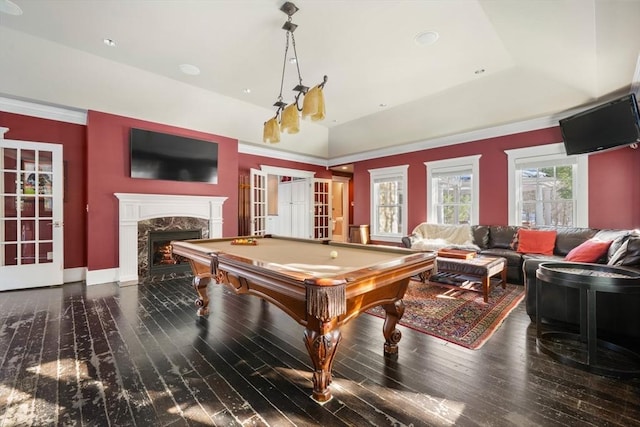 rec room with a tray ceiling, pool table, a high end fireplace, vaulted ceiling, and wood finished floors