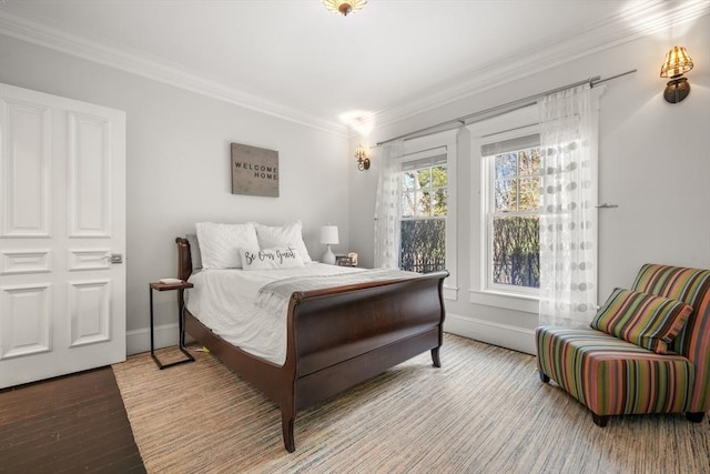 bedroom with baseboards, ornamental molding, and wood finished floors