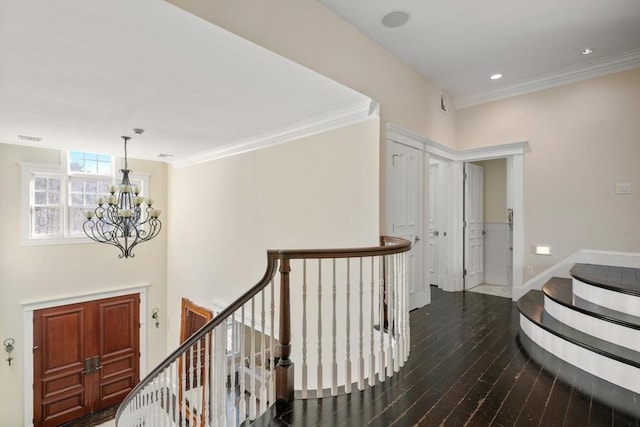 hall with ornamental molding, a chandelier, dark wood finished floors, and an upstairs landing