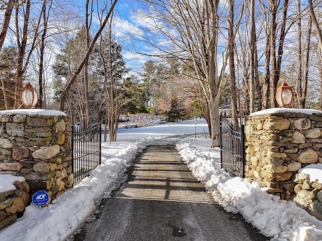 snowy yard featuring a gate