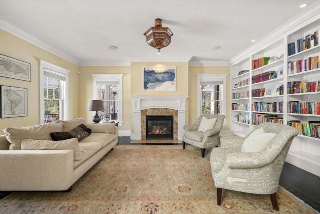 sitting room with a fireplace with flush hearth, built in features, crown molding, and wood finished floors