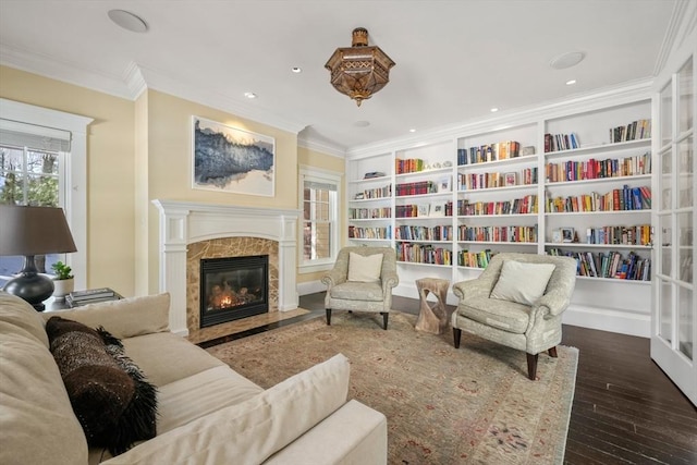 sitting room featuring recessed lighting, a premium fireplace, wood finished floors, built in features, and crown molding