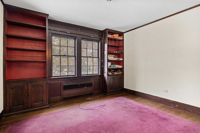 unfurnished room with radiator, crown molding, baseboards, and wood finished floors