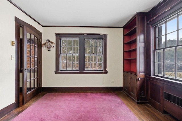 spare room with crown molding, dark wood-style floors, and baseboards