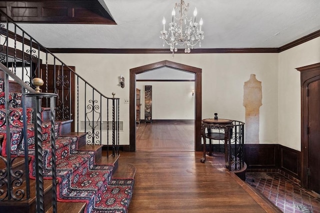 foyer entrance featuring a notable chandelier, stairs, arched walkways, and wood finished floors