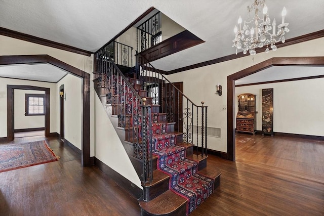 foyer entrance with arched walkways, baseboards, wood finished floors, and crown molding