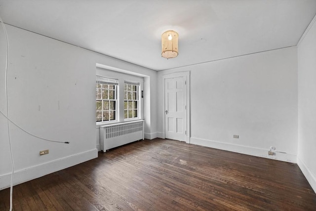 unfurnished room featuring radiator heating unit, baseboards, and wood finished floors