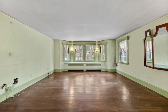 unfurnished room with radiator, baseboards, and wood finished floors