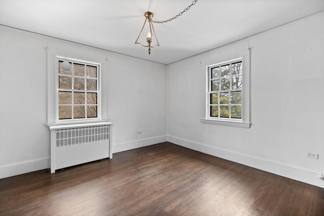 spare room with dark wood-style flooring, radiator heating unit, and baseboards