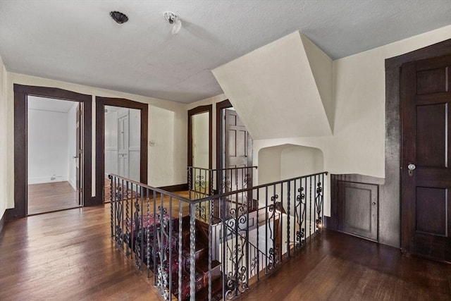 hall featuring baseboards, an upstairs landing, and wood finished floors