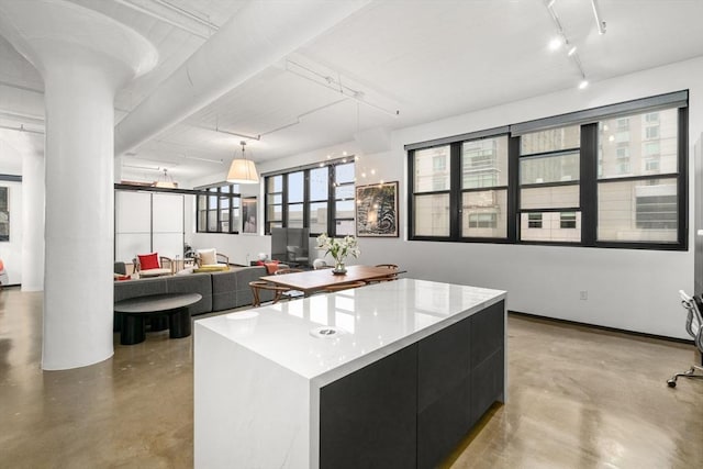 437 D St Unit 4F, Boston, MA 02210 - kitchen featuring concrete flooring, dark cabinetry, ornate columns, and decorative light fixtures