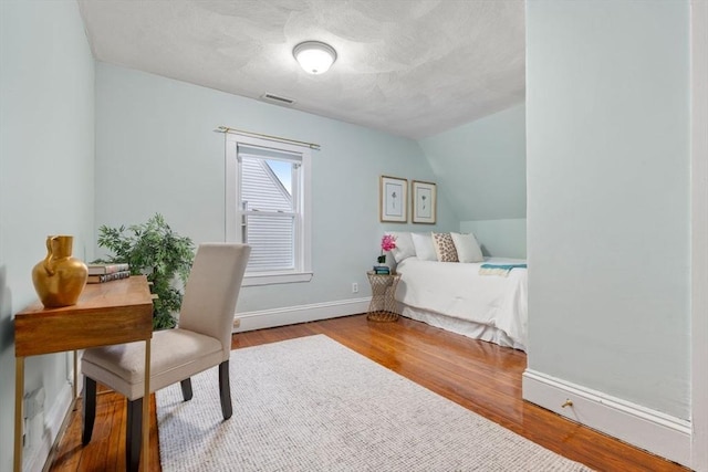 bedroom with wood-type flooring and vaulted ceiling