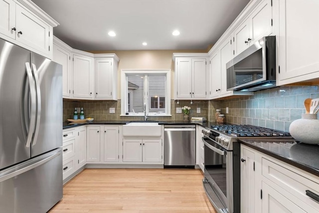 kitchen featuring sink, tasteful backsplash, appliances with stainless steel finishes, light hardwood / wood-style floors, and white cabinets