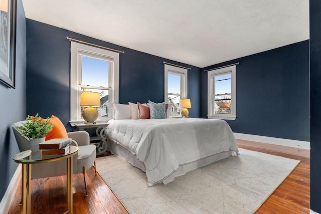 bedroom with multiple windows and hardwood / wood-style flooring