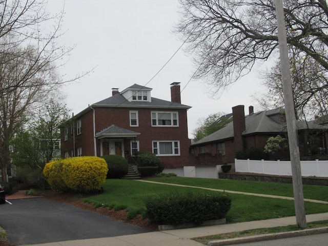 traditional style home with a front yard, fence, brick siding, and a chimney