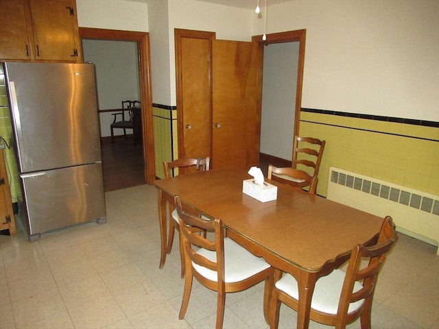 dining area with tile walls, radiator heating unit, and wainscoting