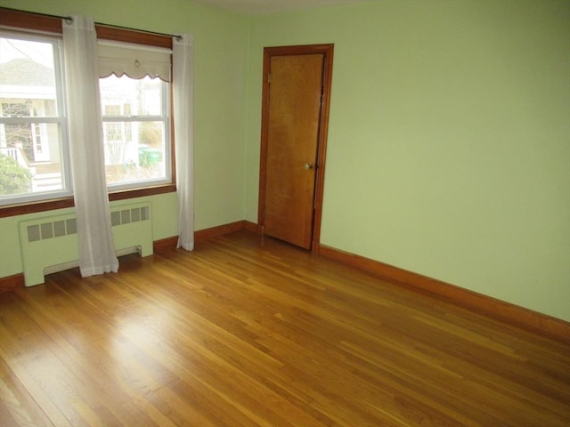 spare room with radiator, baseboards, and light wood-type flooring