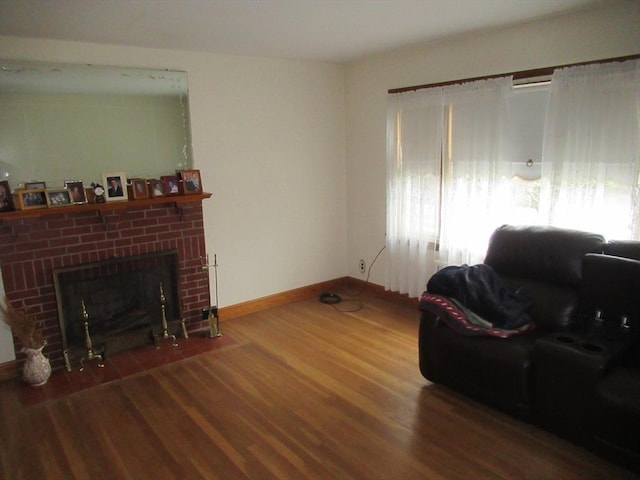 living area featuring a fireplace, baseboards, and wood finished floors