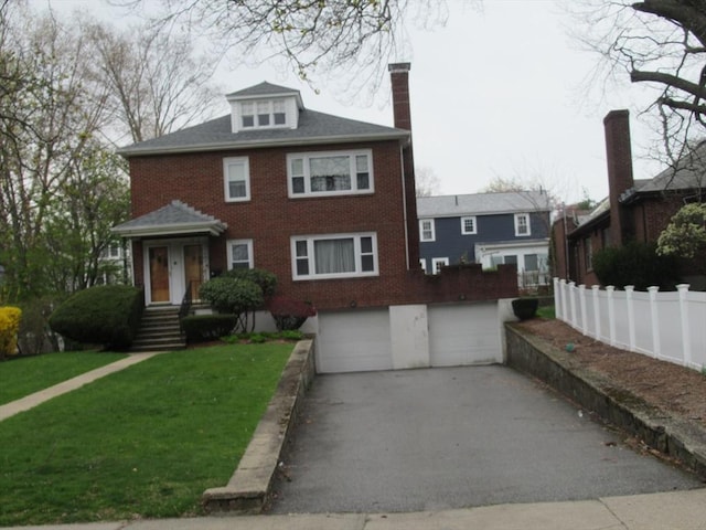 american foursquare style home with driveway, fence, a front yard, an attached garage, and brick siding