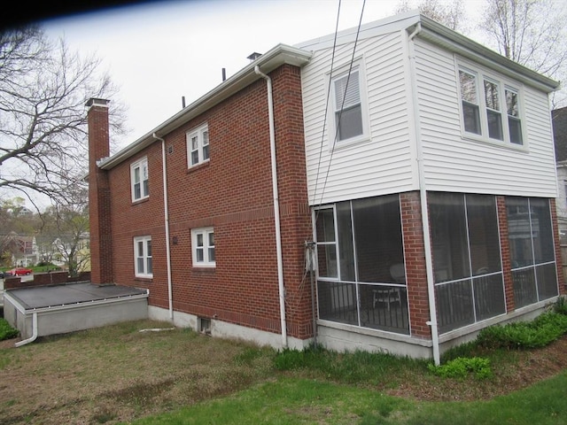 view of property exterior with brick siding and a sunroom