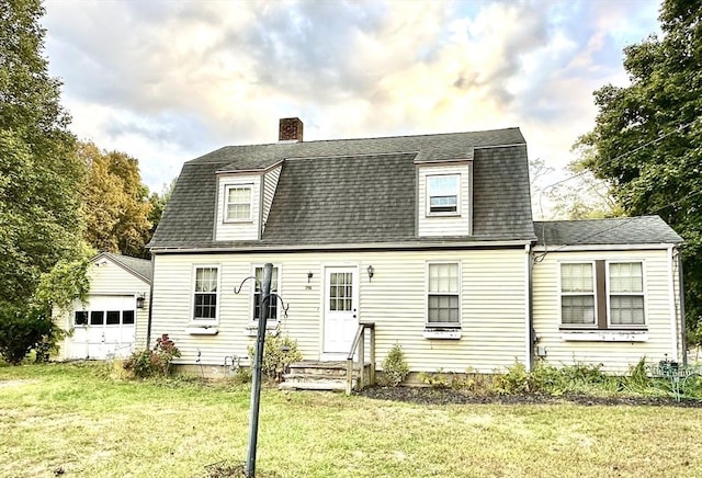 new england style home featuring a garage, a front lawn, and an outdoor structure