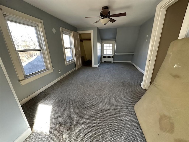 empty room featuring dark colored carpet, ceiling fan, and radiator heating unit