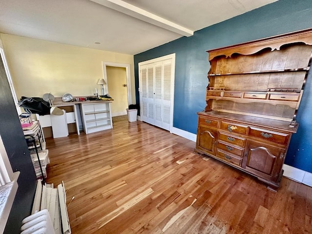 misc room with hardwood / wood-style flooring, beam ceiling, and radiator heating unit