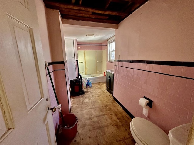 bathroom with toilet, tile walls, and shower / washtub combination