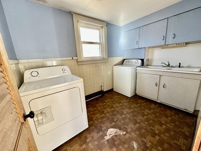 laundry room featuring washing machine and clothes dryer, dark parquet floors, cabinets, and sink