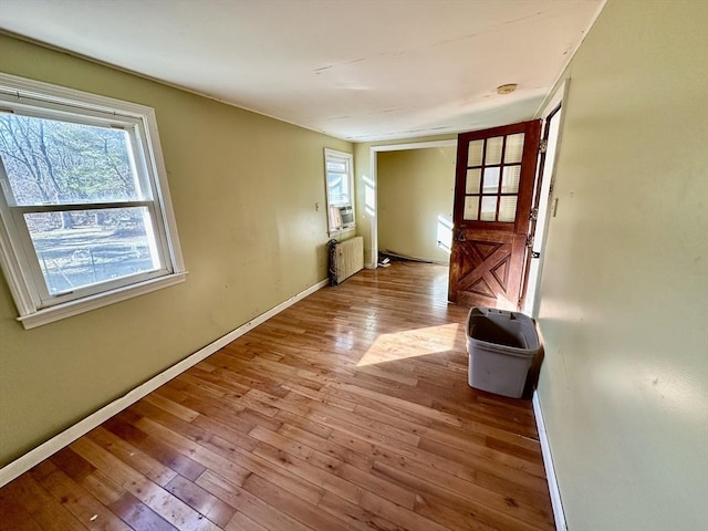 interior space with radiator heating unit, light wood-type flooring, and cooling unit