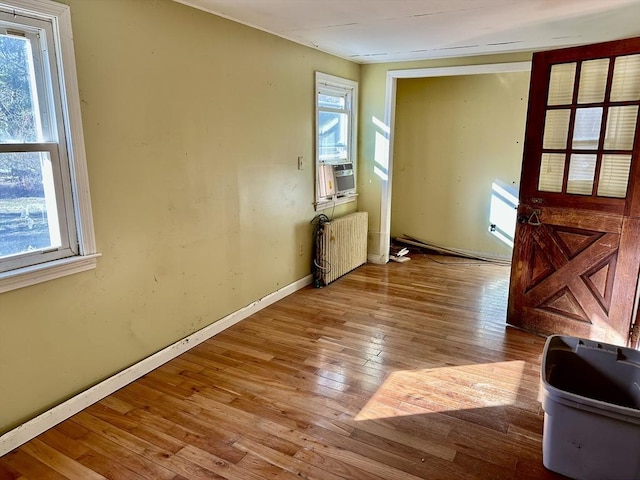 unfurnished room featuring radiator, a wealth of natural light, and light hardwood / wood-style floors